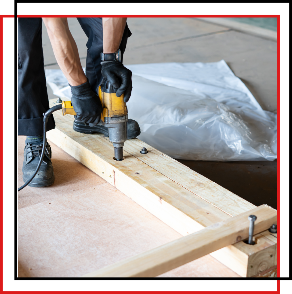 A Person Drilling Screw in Wooden Crate